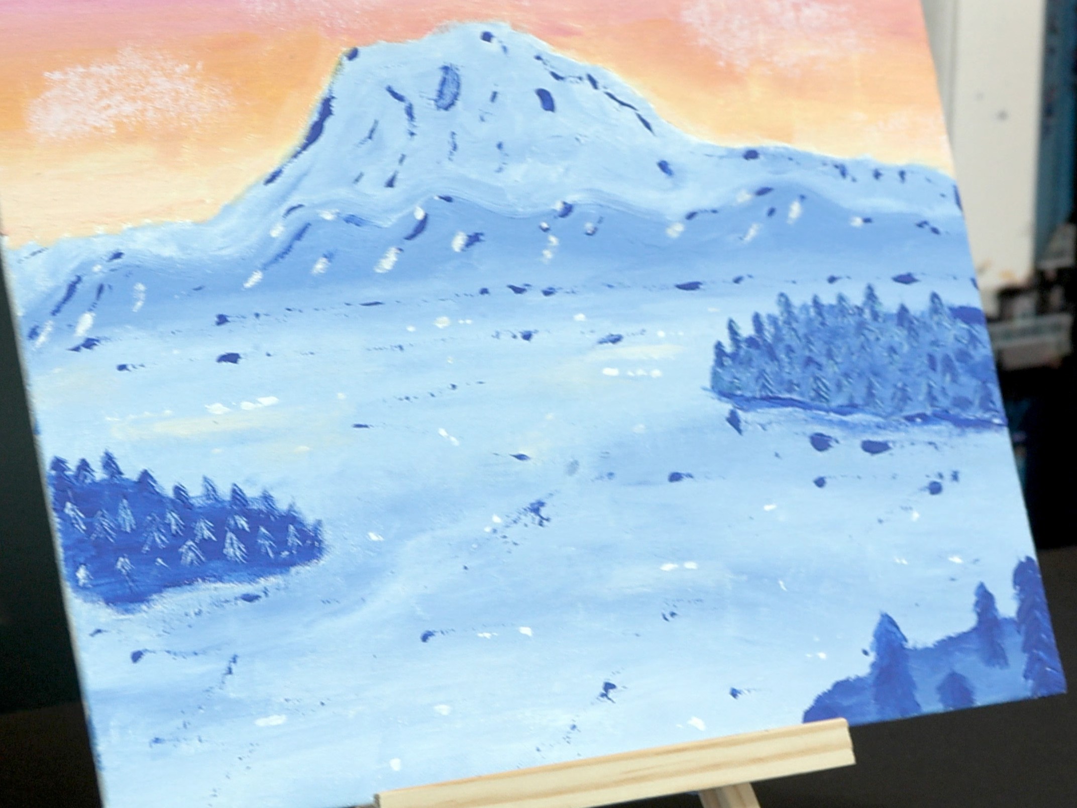 Student created art of a mountain of different hues of blue in front of a sunset.