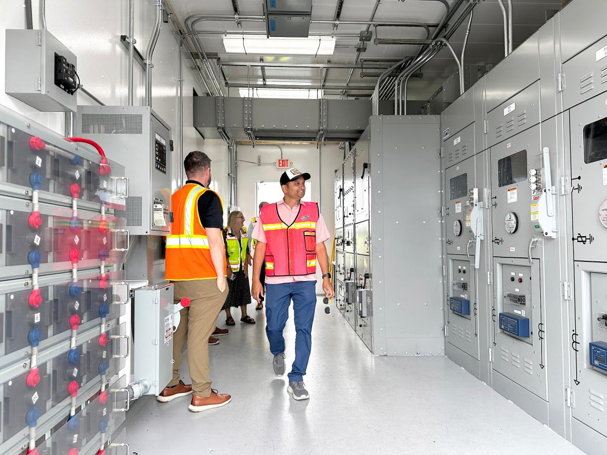 People in reflective safety vests walk through a port terminal shore power substation.
