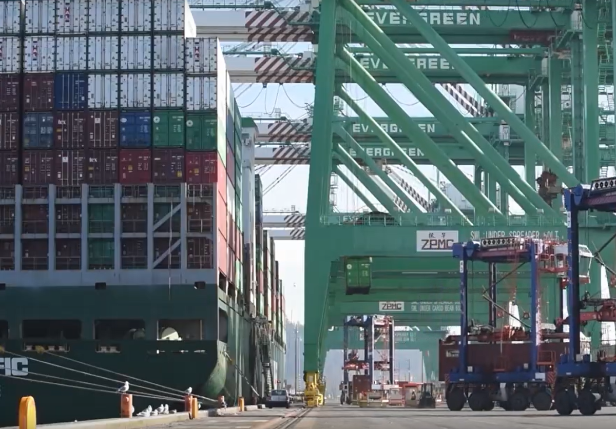 A port terminal with a vessel being unloaded by cranes.